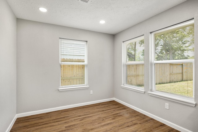 spare room with baseboards, wood finished floors, a textured ceiling, and recessed lighting