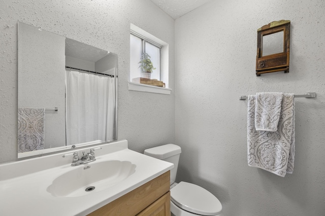 bathroom with curtained shower, a textured wall, toilet, and vanity