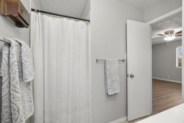 bathroom with a shower with curtain, baseboards, a textured ceiling, and ceiling fan