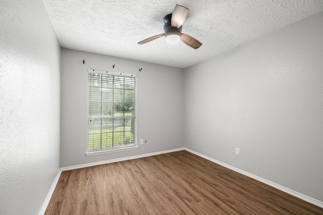 spare room with baseboards, a ceiling fan, wood finished floors, and a textured ceiling