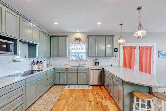 126 Driftwood, Freeport, TX 77541 - kitchen featuring stainless steel appliances, a peninsula, a sink, a kitchen breakfast bar, and light wood-style floors