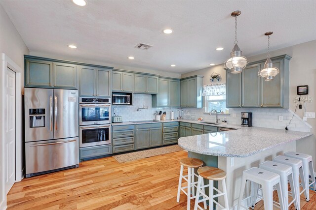 126 Driftwood, Freeport, TX 77541 - kitchen featuring stainless steel appliances, a sink, a peninsula, light wood-style flooring, and a breakfast bar area