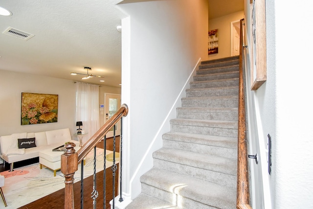 staircase with wood finished floors and visible vents