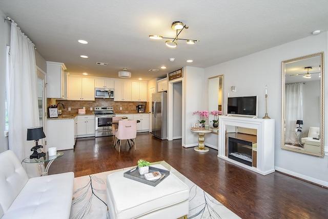 living room featuring baseboards, visible vents, dark wood-style floors, and recessed lighting