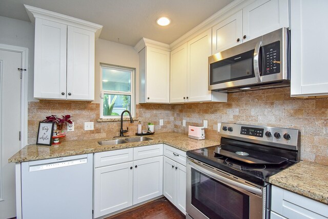 kitchen featuring white cabinets, stainless steel appliances, decorative backsplash, and a sink