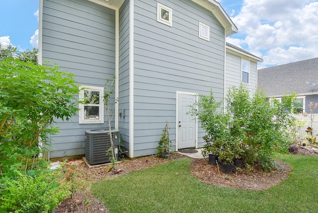 back of house featuring central AC unit and a yard