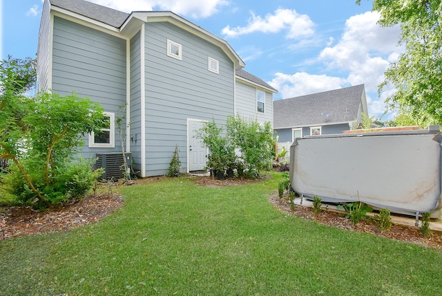 exterior space with roof with shingles, a yard, and cooling unit