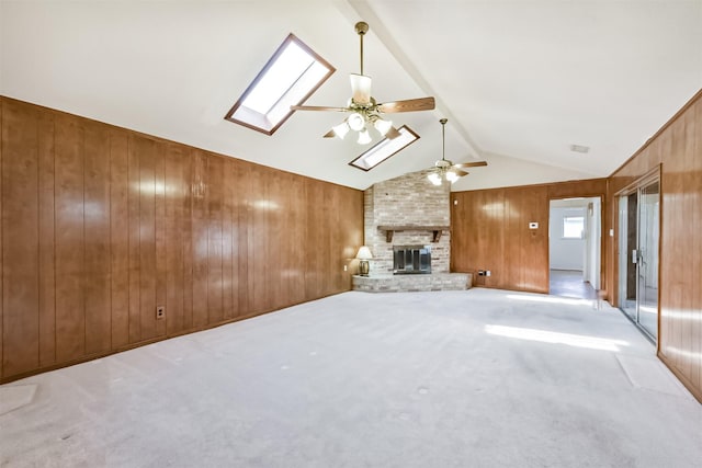 17707 Smooth Rock Falls Dr, Spring, TX 77379 - unfurnished living room with wood walls, a brick fireplace, a ceiling fan, a skylight, and carpet flooring