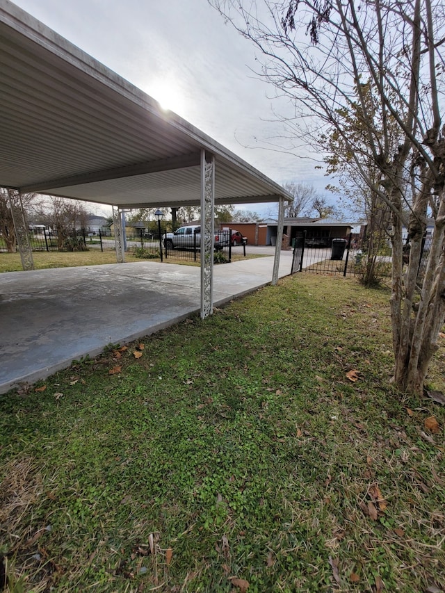 view of yard with fence, a carport, and concrete driveway