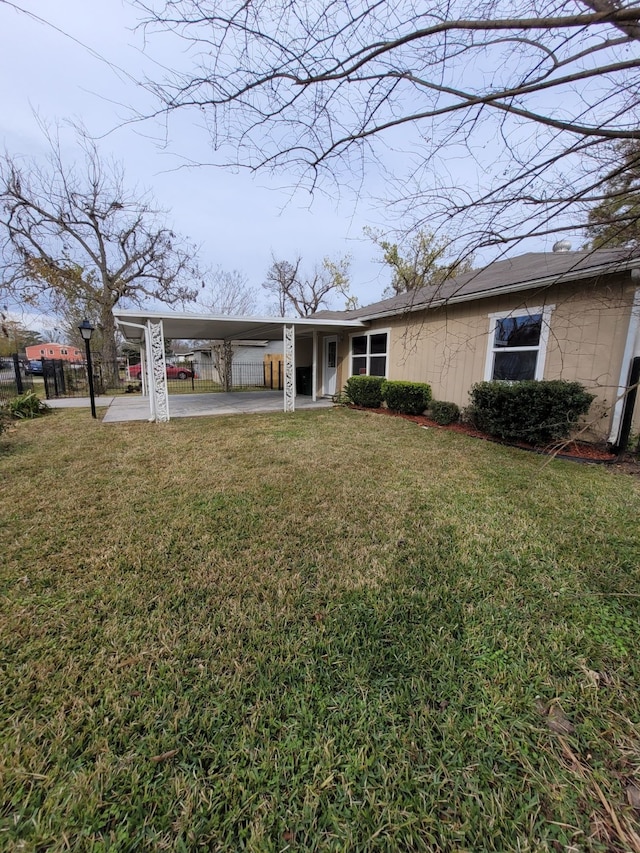 back of property featuring fence, a carport, and a yard