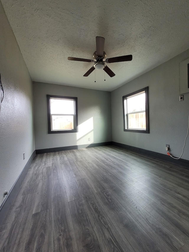 spare room featuring a healthy amount of sunlight, a textured ceiling, ceiling fan, and dark wood finished floors
