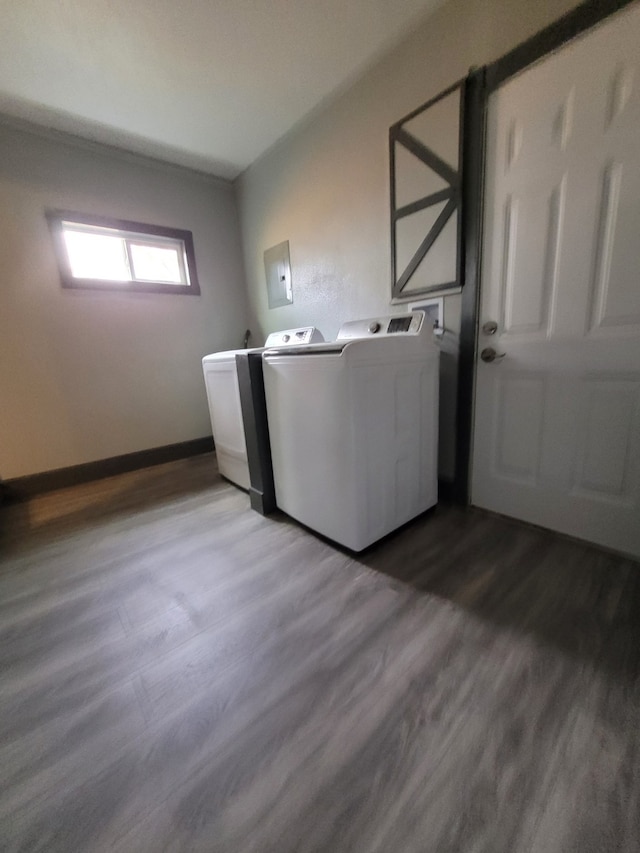 clothes washing area with dark wood-type flooring, washing machine and clothes dryer, baseboards, and laundry area