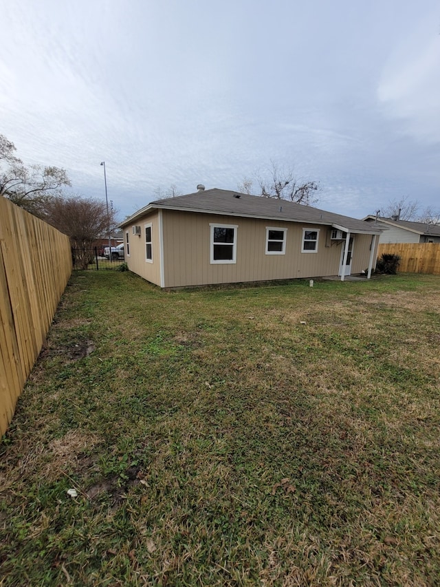 back of house featuring a fenced backyard and a yard