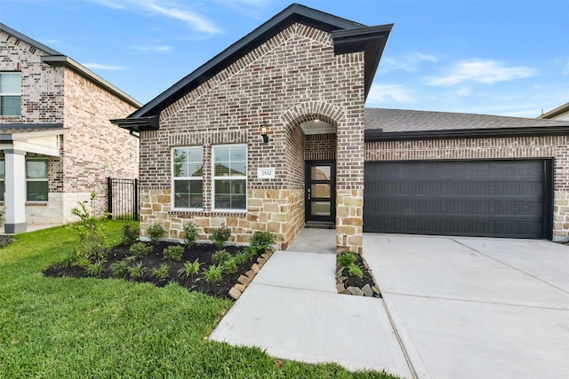 french provincial home with a garage, a front yard, driveway, and brick siding