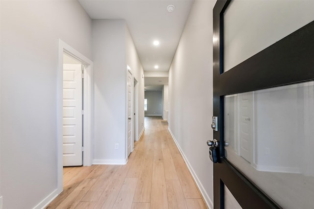corridor featuring baseboards, recessed lighting, and light wood finished floors