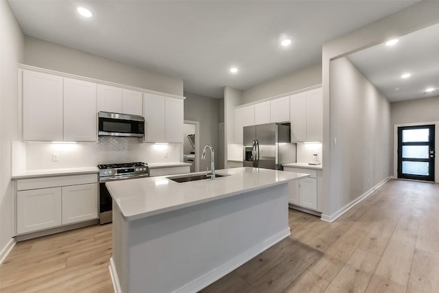 kitchen with a sink, appliances with stainless steel finishes, backsplash, and white cabinets