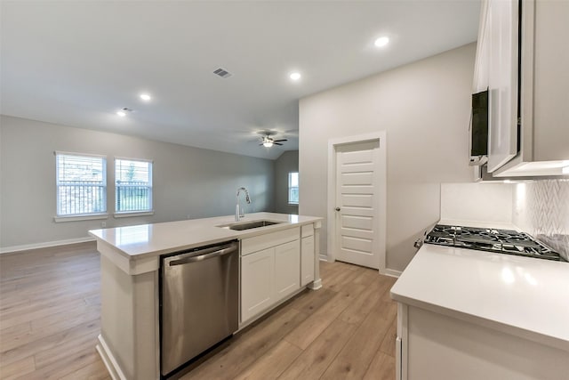 kitchen featuring stainless steel dishwasher, light countertops, white cabinets, a sink, and light wood finished floors