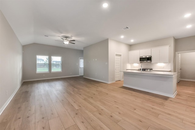 kitchen with visible vents, baseboards, stainless steel microwave, white cabinets, and a ceiling fan