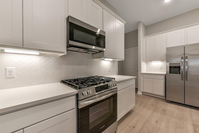 kitchen with backsplash, appliances with stainless steel finishes, light wood-type flooring, light countertops, and white cabinets