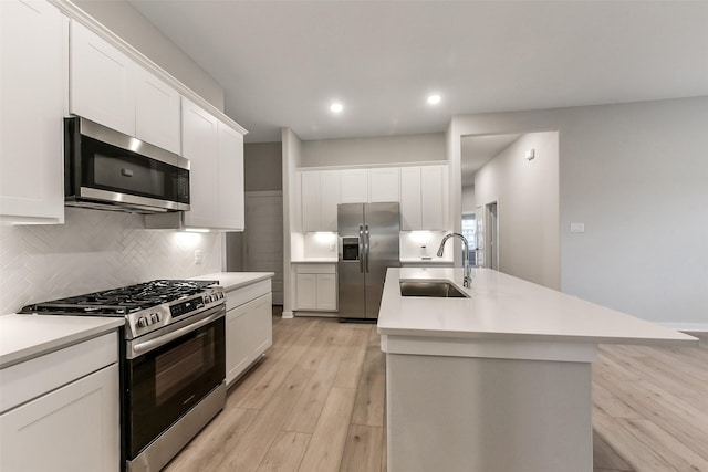 kitchen featuring decorative backsplash, light countertops, a sink, light wood-style flooring, and stainless steel appliances