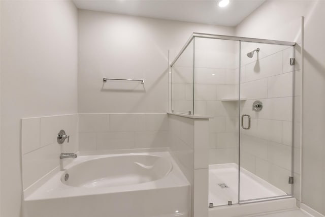 bathroom featuring a stall shower and a bath