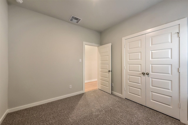 unfurnished bedroom with carpet floors, baseboards, a closet, and visible vents