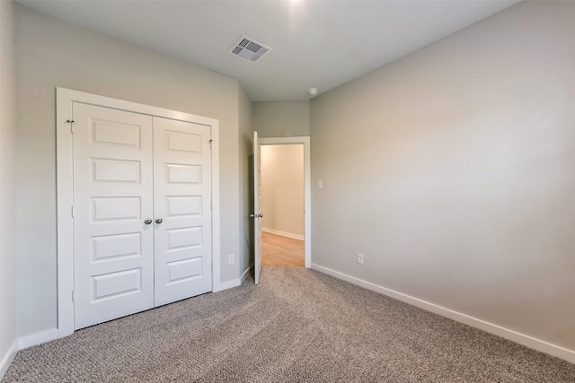 unfurnished bedroom with visible vents, carpet flooring, baseboards, and a closet