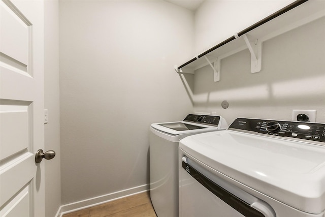 clothes washing area with light wood-style floors, separate washer and dryer, baseboards, and laundry area