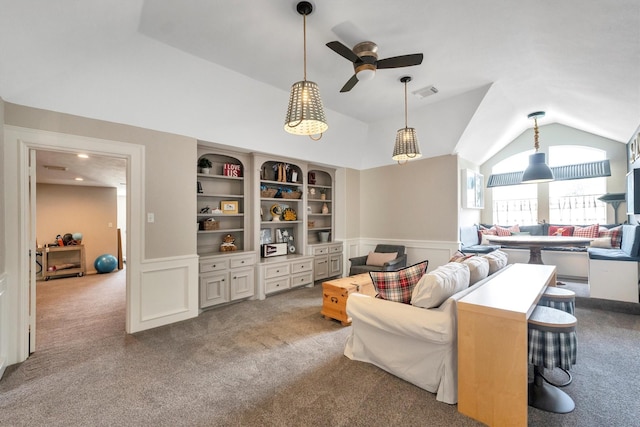 carpeted living area featuring a wainscoted wall, visible vents, ceiling fan, and lofted ceiling