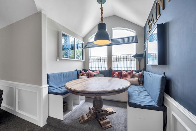 carpeted dining area with vaulted ceiling