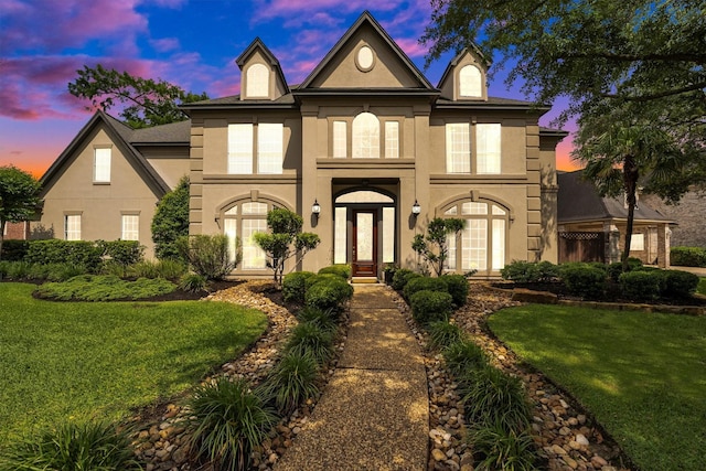 view of front of home with stucco siding and a yard