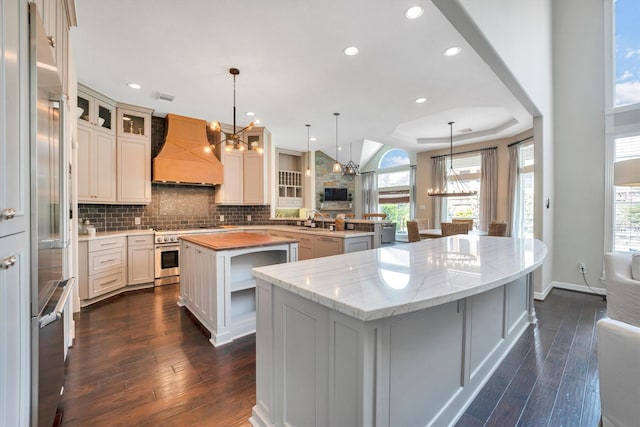 kitchen with a chandelier, dark wood-style floors, a large island, custom exhaust hood, and high end appliances