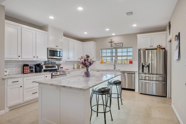 414 N Old Springfield Rd, North Zulch, TX 77872 - kitchen with a kitchen breakfast bar, white cabinets, stainless steel appliances, backsplash, and visible vents