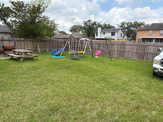 view of yard featuring a residential view, heating fuel, a playground, and a fenced backyard