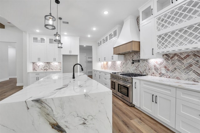 kitchen with backsplash, visible vents, a sink, double oven range, and custom range hood