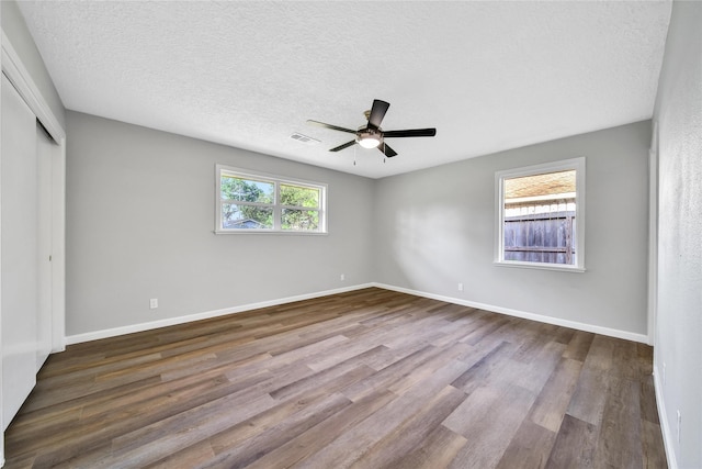 unfurnished bedroom featuring wood finished floors, visible vents, a ceiling fan, a closet, and baseboards