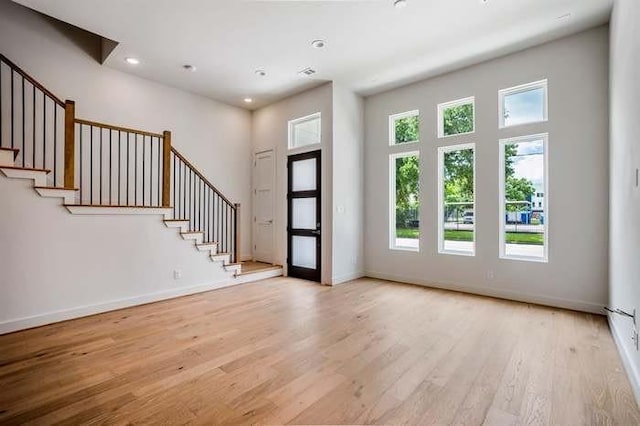 foyer with stairway, a wealth of natural light, and wood finished floors