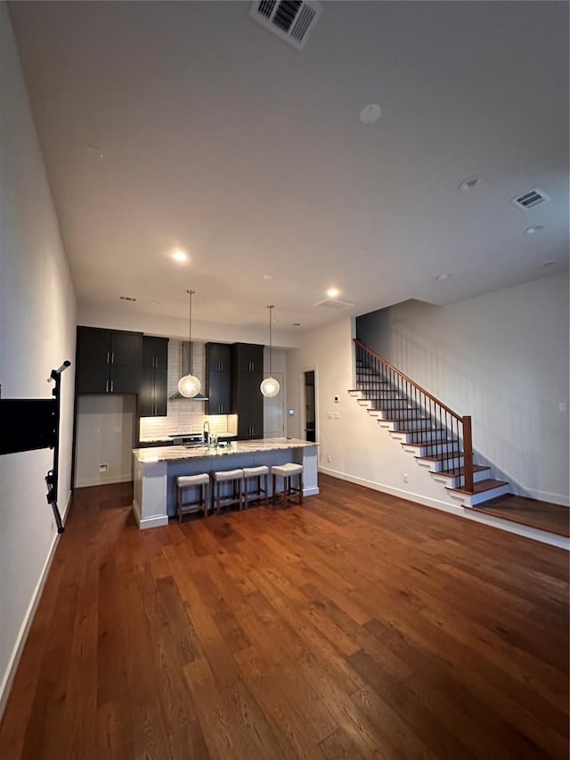 2409 Webster St, Houston, TX 77003 - kitchen featuring light countertops, wall chimney exhaust hood, dark wood-style floors, a kitchen bar, and hanging light fixtures