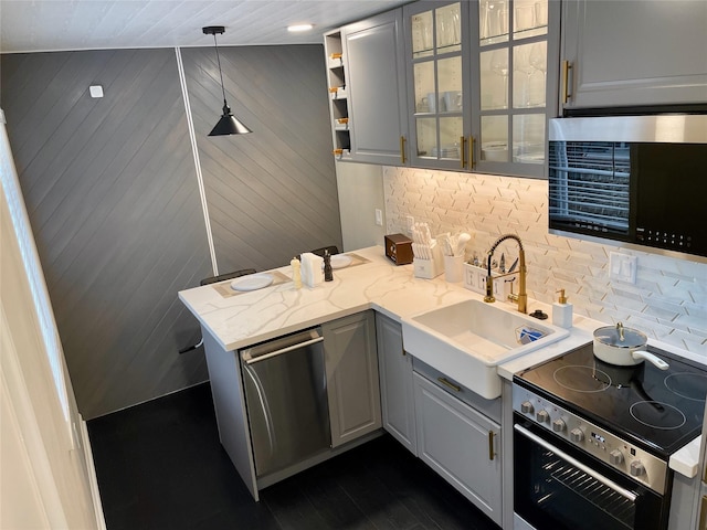 kitchen featuring gray cabinetry, a sink, backsplash, and appliances with stainless steel finishes
