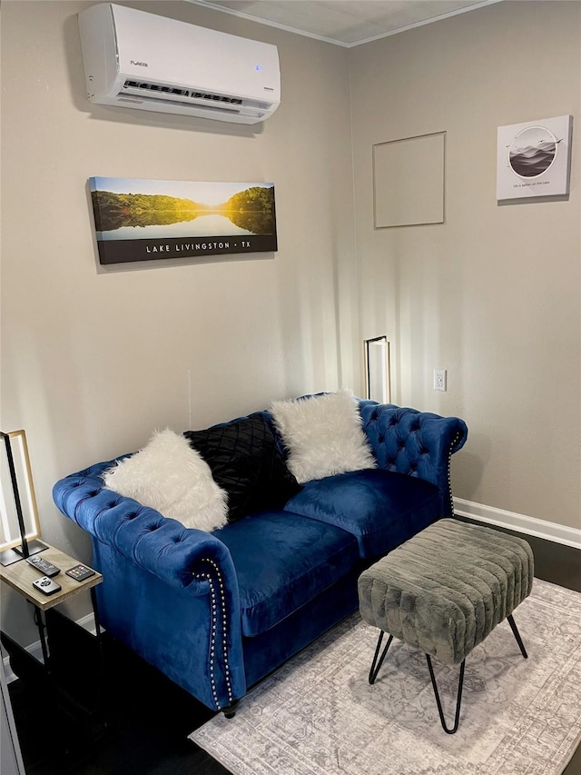 living area with baseboards, a wall unit AC, and wood finished floors