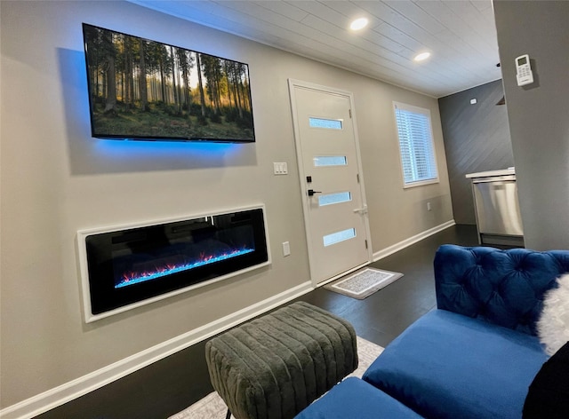 living area with wood finished floors, a glass covered fireplace, wood ceiling, baseboards, and recessed lighting