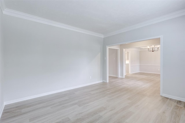 spare room with crown molding, light wood-style flooring, baseboards, and an inviting chandelier