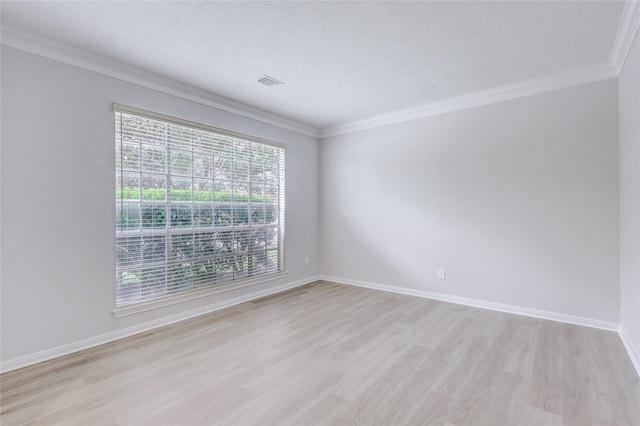 empty room featuring crown molding, visible vents, light wood-style flooring, and baseboards