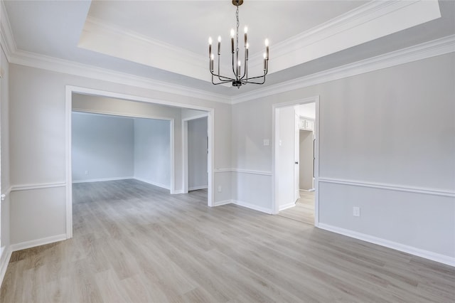 spare room with baseboards, a raised ceiling, light wood-style floors, and an inviting chandelier