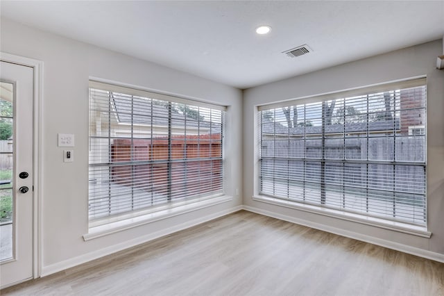 unfurnished dining area featuring baseboards, visible vents, and wood finished floors