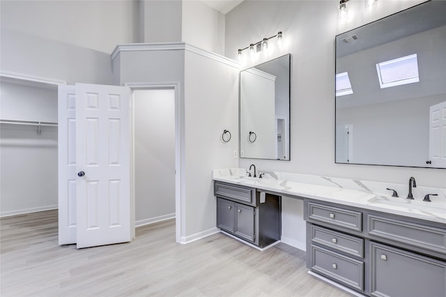 full bath featuring double vanity, wood finished floors, a spacious closet, and a sink