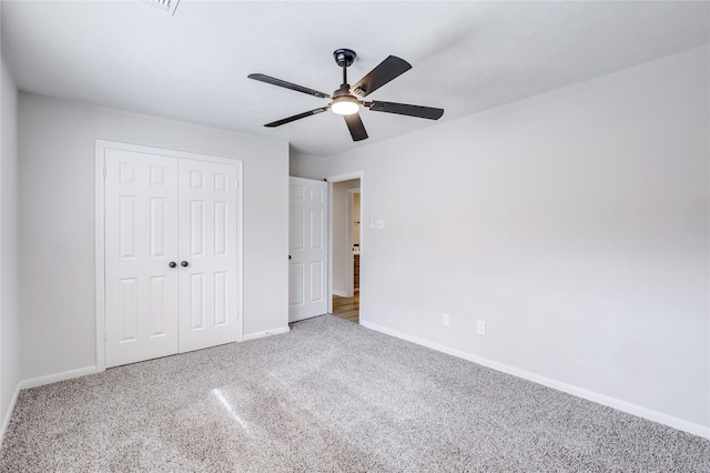 unfurnished bedroom featuring carpet, baseboards, a closet, and a ceiling fan