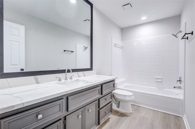 bathroom with toilet, tub / shower combination, wood finished floors, visible vents, and vanity