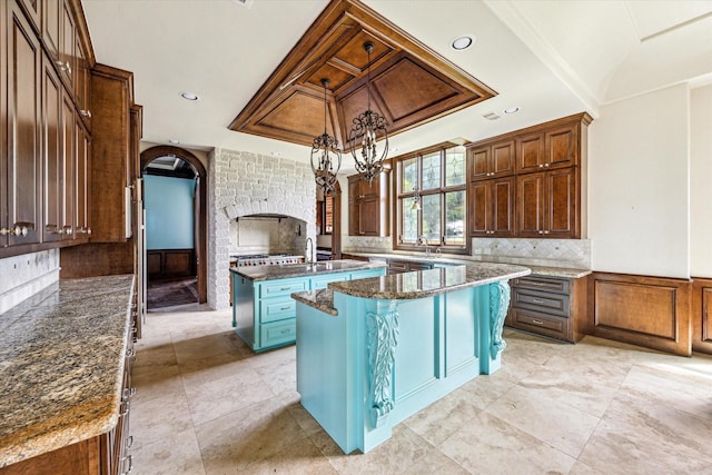kitchen featuring a kitchen island with sink, arched walkways, tasteful backsplash, recessed lighting, and an inviting chandelier