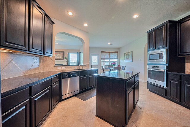 20322 Fossil Valley Ln, Cypress, TX 77433 - kitchen with stainless steel appliances, dark countertops, arched walkways, recessed lighting, and backsplash